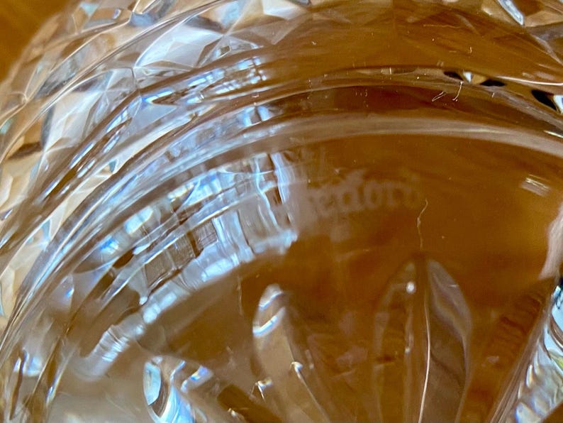 Puede incluir: Primer plano de un objeto de vidrio transparente con un patr&oacute;n de corte de diamante. El vidrio tiene l&iacute;neas curvas y una superficie texturizada. La palabra "tedoro" es visible en el vidrio.