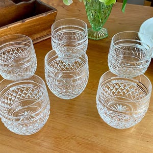 Puede incluir: Seis vasos de cristal tallado transparente con un dise&ntilde;o de diamantes y estrellas. Los vasos est&aacute;n colocados sobre una mesa de madera, mostrando su intrincado dise&ntilde;o. Adecuado para servir bebidas.