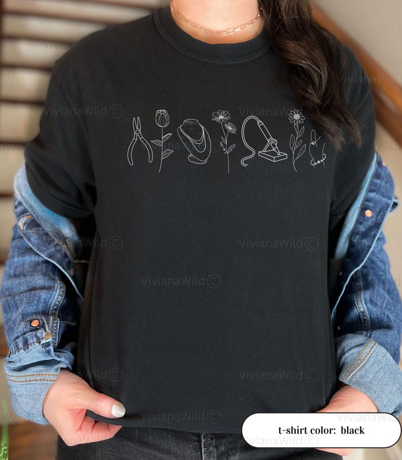May include: Black crew neck t-shirt with a white line drawing of tools and flowers. The shirt has the text "t-shirt color: black" at the bottom. The shirt is worn with a denim jacket.