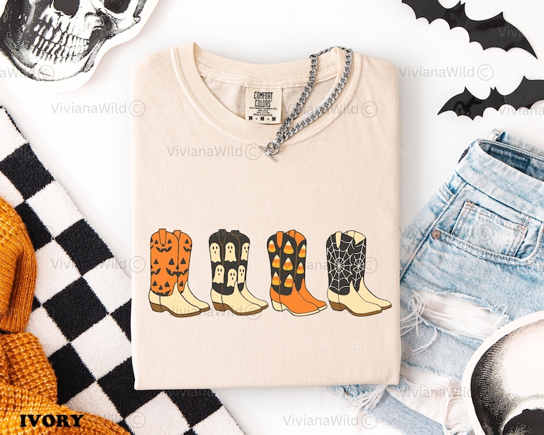 Puede incluir: Camiseta color marfil con cuatro botas de vaquero con dise&ntilde;os de Halloween. Las botas son naranjas, negras y blancas, con calabazas, fantasmas, caramelos y telara&ntilde;as. La camiseta tiene una etiqueta Comfort Colors y se combina con pantalones cortos vaqueros.