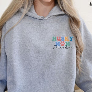 May include: A gray hooded sweatshirt with the text "HUSKY MOM Meeka" in colorful letters and paw prints on the front.