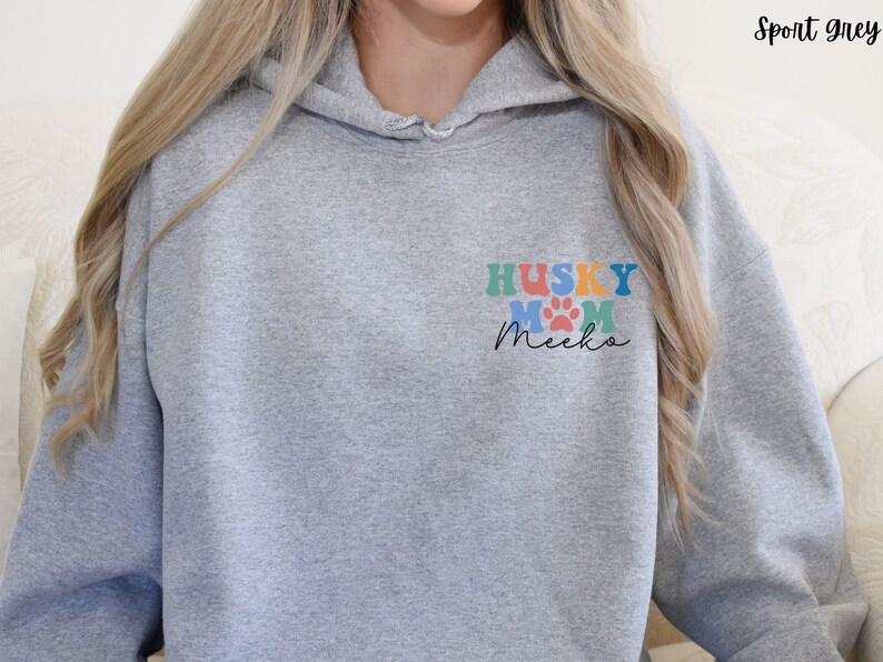 May include: A gray hooded sweatshirt with the text "HUSKY MOM Meeka" in colorful letters and paw prints on the front.