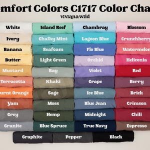 May include: Color chart displaying Comfort Colors C1717 colors. The chart features a variety of colors, including white, ivory, banana, butter, mustard, terracotta, burnt orange, yam, grey, and granite. Each color is labeled with its name.
