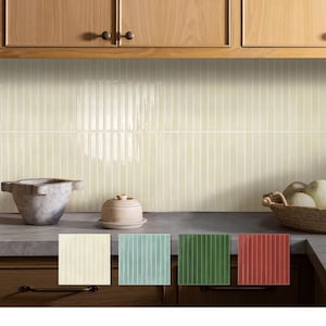 Può includere: Un paraschizzi da cucina con piastrelle rettangolari verticali e lucide di colore crema. Sotto il paraschizzi, sono esposti quattro campioni di piastrelle quadrate in crema, blu-verde chiaro, verde scuro e rosso terracotta, con scanalature.
