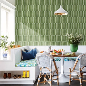 K&ouml;nnte beinhalten: Ein heller, einladender Fr&uuml;hst&uuml;cksbereich mit einem runden Holztisch und zwei Korbst&uuml;hlen. Der Raum verf&uuml;gt &uuml;ber eine eingebaute wei&szlig;e Bank mit blauen Kissen und einem floralen Kissen. Eine gr&uuml;n-wei&szlig;e Fliesenwand bildet einen stilvollen Hintergrund.