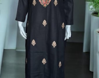 May include: Black embroidered salwar kameez. The long-sleeved tunic features a detailed floral design in shades of orange, gold, and green around the neckline. Matching pants complete the ensemble. Small gold embroidered leaf patterns are scattered across the tunic.