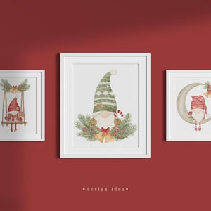 May include: Three white framed prints featuring watercolour illustrations of gnomes. The first gnome is on a swing, the second gnome is holding a candy cane, and the third gnome is sitting on a crescent moon.