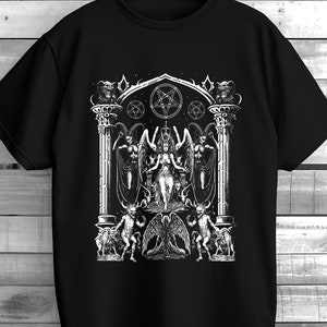 May include: Black t-shirt featuring a detailed white graphic of a gothic scene with a central figure, angels, demons, and a pentagram. The design is intricate and detailed, creating a striking visual on the dark fabric. The shirt is hanging on a wooden hanger.