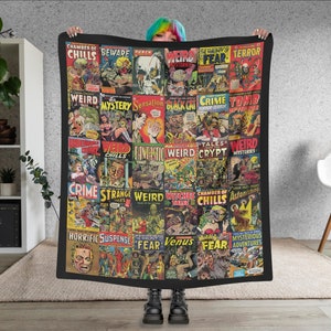May include: A black and white blanket with a collage of vintage comic book covers featuring horror and mystery themes. The covers feature titles like "Chamber of Chills", "Weird Mysteries", "Crime Tomb", "Strange Weird Tales", "Witches Tales", and "Venus Fear".
