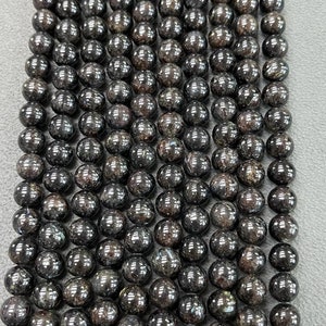 May include: A strand of black gemstone beads with a shimmery, iridescent finish. The beads are round and uniform in size, creating a smooth and elegant look.