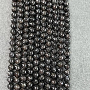 May include: A strand of black round gemstone beads. The beads have a speckled, glittery appearance.