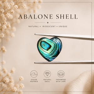 May include: A heart-shaped abalone shell piece with iridescent blue and green tones held by metal tweezers. The image includes the text ABALONE SHELL, NATURAL, IRIDESCENT, UNIQUE, OCEAN INSPIRED, NATURAL SHELL, and HANDMADE WITH CARE.