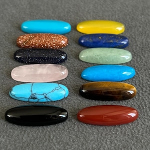 May include: Assortment of 12 oval-shaped gemstone cabochons in various colors, including turquoise, yellow, blue, green, pink, brown, black, and red.