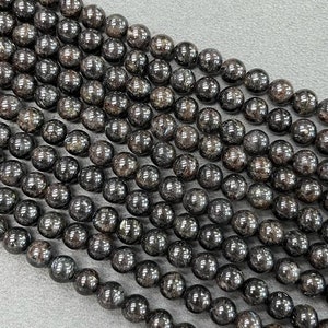 May include: A strand of black gemstone beads with a shimmery, metallic finish. The beads are round and uniform in size, creating a smooth and elegant look.