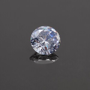May include: A clear round diamond gemstone with many facets, reflecting light.