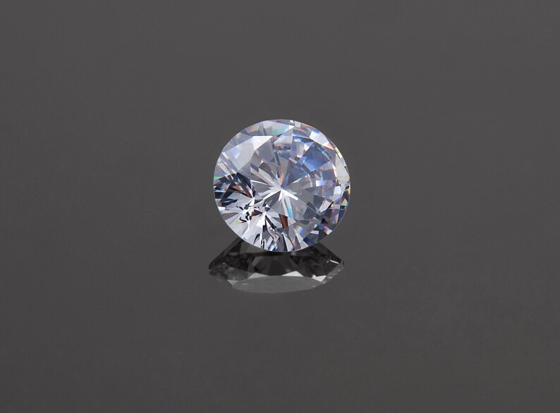 May include: A clear round diamond gemstone with many facets, reflecting light.