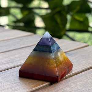May include: A seven-layered crystal pyramid with a red, orange, yellow, white, blue, indigo, and violet color scheme. The pyramid is made of natural stones and is a popular choice for meditation and energy healing.