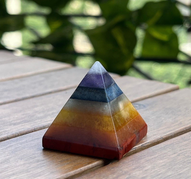 May include: A seven-layered crystal pyramid with a red, orange, yellow, white, blue, indigo, and violet color scheme. The pyramid is made of natural stones and is a popular choice for meditation and energy healing.
