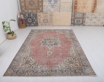 May include: A vintage-style rug with a faded red center and intricate floral patterns in beige and blue. The rug has a distressed look and a worn, faded appearance.