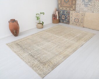 May include: A light beige area rug with a faded floral pattern. The rug has a distressed look and is made of natural fibers.