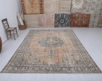 Puede incluir: Gran alfombra rectangular de estilo vintage con un diseño de medallón central en tonos azules y beige. La alfombra presenta un borde intrincado y un aspecto envejecido, lo que sugiere una pieza antigua. La alfombra está colocada sobre un suelo claro. Mide aprox. 300 cm x 200 cm.