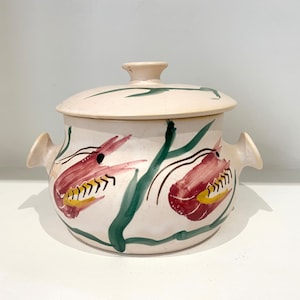 May include: A white ceramic casserole dish with a lid, featuring a hand-painted design of two red shrimp with yellow and green accents. The dish has two handles on the sides.