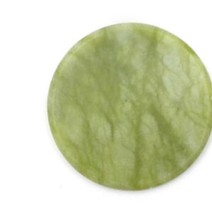 May include: A round, pale green jade stone with a smooth, polished surface. The stone has subtle variations in color and texture, with a marbled appearance. The jade is set against a white background.
