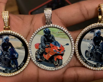 May include: Three gold and silver pendants with a diamond-encrusted border. Each pendant features a photo of a person riding a motorcycle. The text "LOOK TWICE SAVE A LIFE" is printed on the bottom of each pendant.