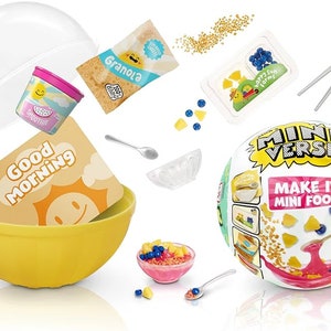 May include: A Miniverse Make It Mini Food kit with a yellow bowl, a pink smoothie cup, a granola packet, a clear bowl, a spoon, a container of blueberries, a container of pineapple, a yellow card with the text "Good Morning", and a pink bowl with cereal and blueberries.