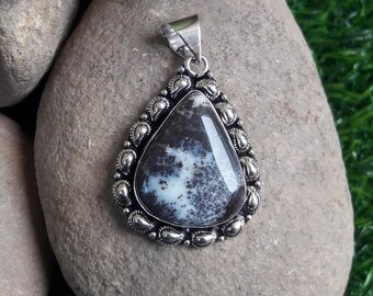 May include: A silver pendant with a black and white agate stone set in a teardrop shape. The stone has a swirling pattern of black and white.