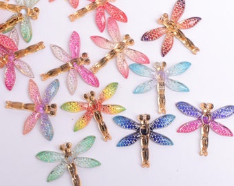 May include: Assortment of colorful dragonfly-shaped embellishments with gold accents. These decorative pieces are perfect for adding a touch of whimsy to crafts, jewelry, and other projects.