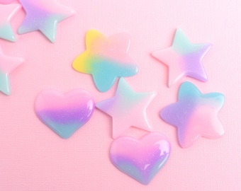 May include: A collection of iridescent pastel pink, blue, and purple heart and star shapes on a pink background.