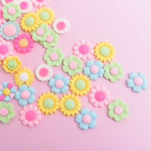 May include: Assortment of colorful plastic flower-shaped buttons in pastel shades of pink, blue, yellow, and green.