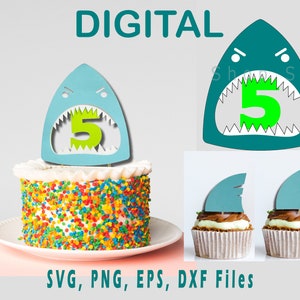 May include: A blue shark cake topper with a green number 5 inside its mouth. The topper is on top of a white cake with colourful sprinkles. There are also two smaller blue shark fin toppers on top of cupcakes.