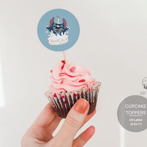 May include: A blue and white cupcake topper featuring a cartoon character with blue fur and big eyes, holding a lit candle and sitting on top of a cake. The topper is printed on a round, white cardstock and is attached to a wooden stick. The text "CUPCAKE TOPPERS" is printed in black on a gray background. The text "US Letter (8.5x11)" is printed in black below the text "CUPCAKE TOPPERS".