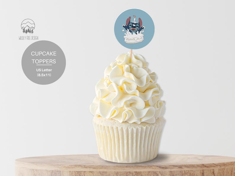 May include: Blue and white cupcake topper featuring a cartoon character with a blue body and red ears, holding a candle and sitting on a white cake. The topper is on a wooden surface.