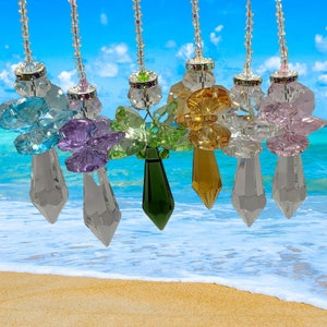 May include: Seven crystal suncatchers with a butterfly design in various colors, including blue, purple, green, yellow, and pink. Each suncatcher has a teardrop-shaped crystal pendant.