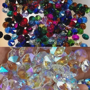 May include: A selection of multi-coloured crystal beads, including red, blue, green, and clear. The beads have a sparkling, iridescent appearance, reflecting light. The image is a close-up, highlighting the intricate cuts and shapes. These beads are suitable for jewellery making.