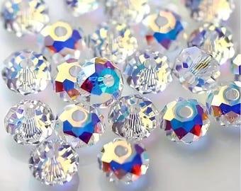 May include: A collection of clear, faceted crystal beads featuring an iridescent finish that reflects vibrant rainbow colors. Each round bead has a central hole and a multi-faceted surface that catches the light, creating a sparkling effect.