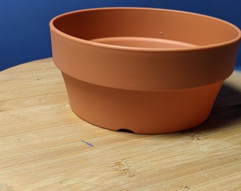 Shallow 5" D x  2.5" H  pot plastic that have the shape and color of a shallow terracotta pot.