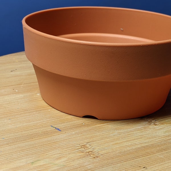 Shallow 5" D x  2.5" H  pot plastic that have the shape and color of a shallow terracotta pot.