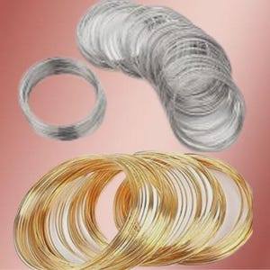 May include: A collection of metallic craft wire coils arranged in two distinct groups. The top section features multiple silver-colored wire loops, while the bottom section displays several gold-colored wire loops, all formed into circular shapes.