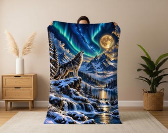 Puede incluir: Una manta rectangular con un estampado digital vibrante de un lobo aullando en un acantilado nevado. La escena incluye una luna llena, un cielo estrellado con auroras boreales verdes, montañas cubiertas de nieve, pinos y un río.