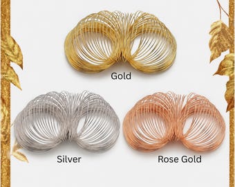 May include: Three coiled wire bracelets arranged in a triangular formation. The top bracelet is gold, the bottom left is silver, and the bottom right is rose gold. Each bracelet consists of multiple thin, circular wire loops. Text labels Gold, Silver, and Rose Gold are positioned below each corresponding item.