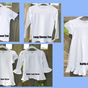 K&ouml;nnte beinhalten: F&uuml;nf wei&szlig;e, leere T-Shirts und ein wei&szlig;es R&uuml;schenkleid. Die T-Shirts sind auf Kleiderb&uuml;geln aufgeh&auml;ngt und haben verschiedene &Auml;rmell&auml;ngen: Kurzarm, Langarm, R&uuml;schen-Kurzarm und R&uuml;schen-Langarm. Das Kleid hat einen R&uuml;schenbesatz am Saum. Der Text unter jedem Kleidungsst&uuml;ck identifiziert den Stil: Kurzarm-T-Shirt, Langarm-T-Shirt, R&uuml;schen-Kurzarm-T-Shirt, R&uuml;schen-Langarm-T-Shirt und R&uuml;schenkleid.