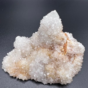 May include: A large cluster of clear quartz crystals with a white, cloudy appearance. The crystals are clustered together in a natural formation, creating a unique and interesting shape.