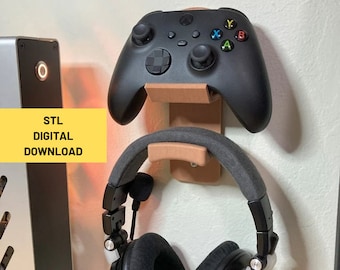 May include: A 3D printed wall mount for a gaming headset and controller. The mount is made of brown plastic and has a black headset and a black Xbox controller attached to it. The text "STL DIGITAL DOWNLOAD" is visible in the image.