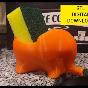 May include: Orange 3D printed elephant shaped sponge holder with a yellow and green sponge inside.