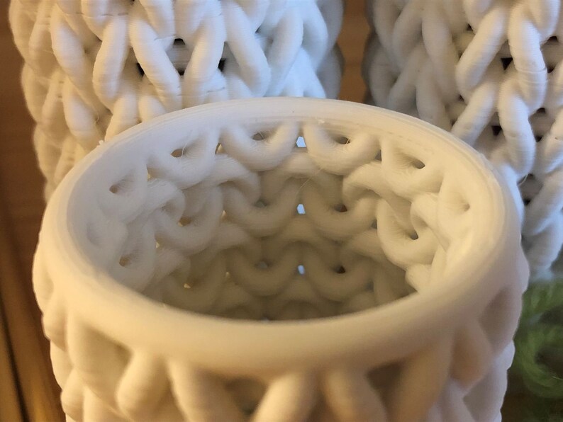 May include: Close-up of a white, 3D printed, cylindrical object with a lattice pattern. The object is hollow and the inside is visible.