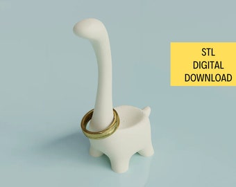 May include: White 3D printed dinosaur ring holder with a gold ring on its neck. STL DIGITAL DOWNLOAD text is in the background.